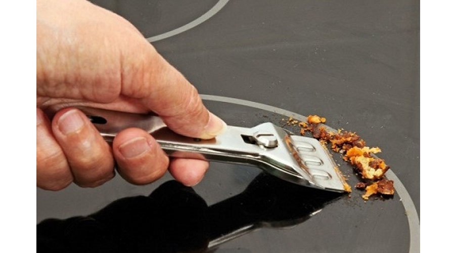 Làm sạch vết bẩn khô trên mặt bếp điện từ bằng dao chuyên dụng
