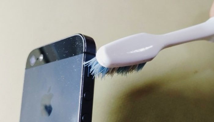 Lại với bàn chải đánh răng làm sạch các nút smartphone
